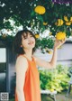 A woman in an orange dress holding a bunch of oranges.