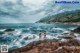 A couple of people standing on top of a rocky beach.