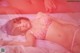 A woman laying on a bed in a pink lingerie.