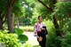 A woman in a kimono standing in a park holding a fan.