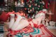 A woman in a red bikini laying on a blanket in front of a Christmas tree.