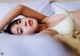 A woman laying on top of a bed in a white bra.