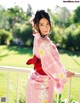 A woman in a pink kimono standing on a balcony.