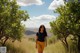 A woman walking down a dirt road in a field.